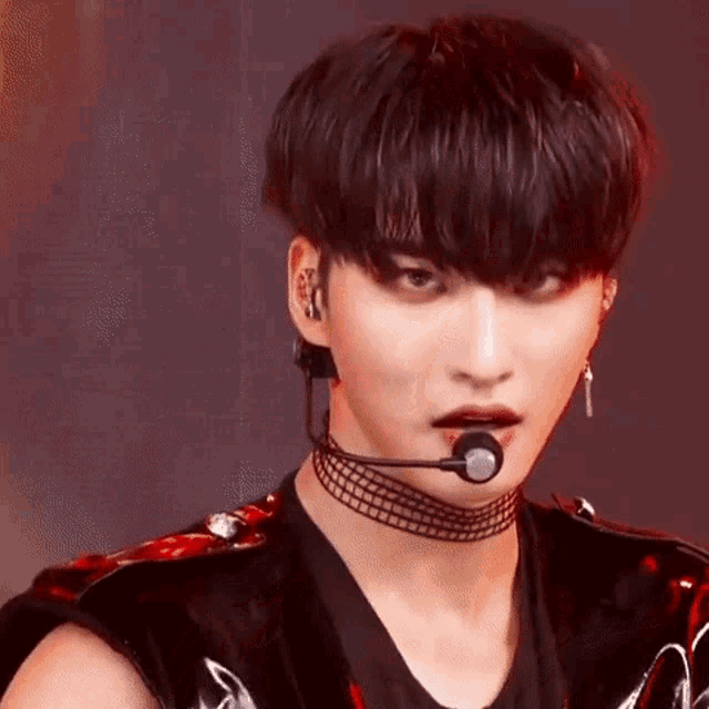 a close up of a person wearing a choker and a microphone in their mouth .