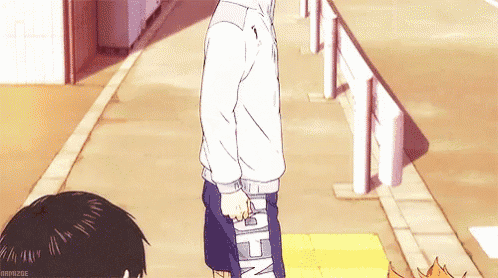 a man in a white jacket is walking down a sidewalk holding a skateboard .