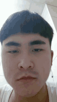 a close up of a person 's face with a white tank top on
