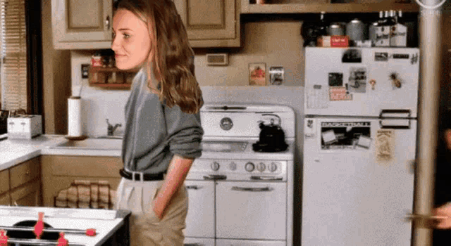 a woman is standing in a kitchen with a refrigerator that has a sticker on it that says ' coca-cola '