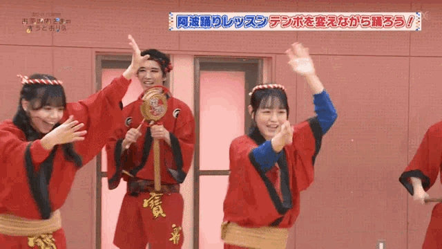a group of people wearing red kimonos are dancing in front of a sign that says ' aoi ' on it