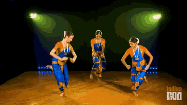three women are dancing in front of a green light and the words indian nyoa are visible