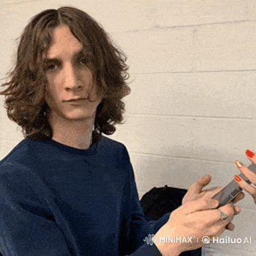 a young man with red nails is holding a cell phone in his hand