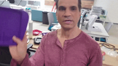 a man in a purple shirt is holding a purple piece of paper in his hand