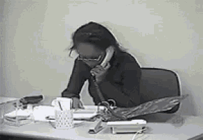 a woman sitting at a desk talking on a cell phone