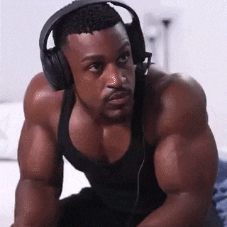 a very muscular man wearing headphones is sitting on a couch .