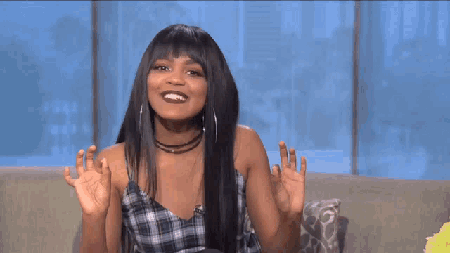 a woman sitting on a couch with her hands up