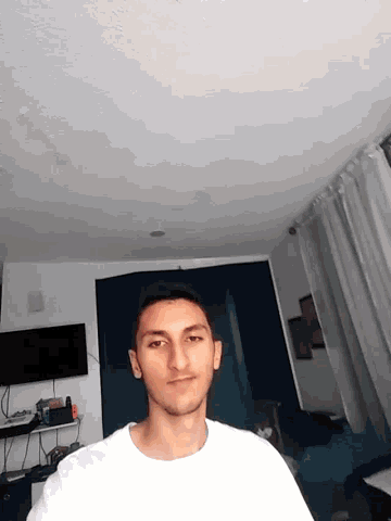 a man in a white shirt stands in front of a television