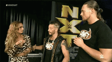 two men and a woman are standing in front of a sign that says nxt on it