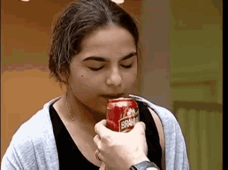 a woman is drinking from a can that says brahma on it