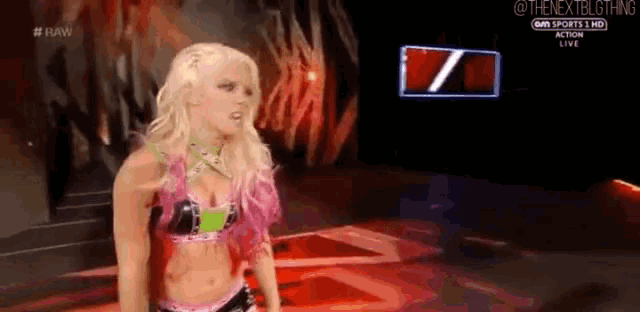 a female wrestler is standing on a stage in front of a screen .