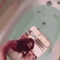 a person is holding a remote control in a bathtub filled with water .