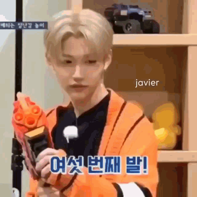a young man is holding a toy gun in front of a shelf with toys on it .