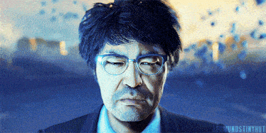 a close up of a man wearing glasses and a suit with the words leomundstinyhut written below him