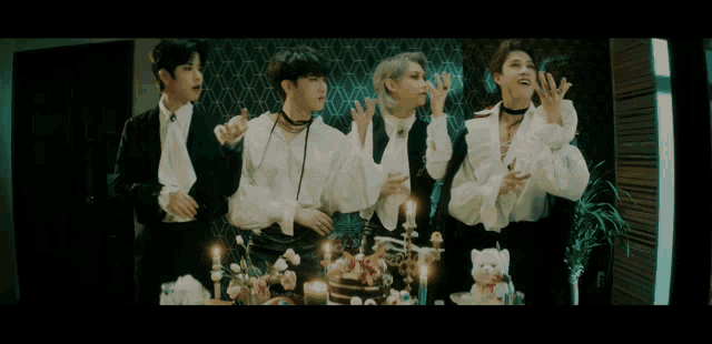 a group of young men are standing around a table with candles on it