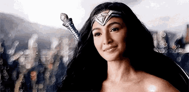 a woman in a wonder woman costume is smiling and holding a sword in her hand .