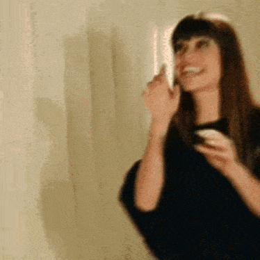 a woman is talking on a cell phone in front of a white wall .