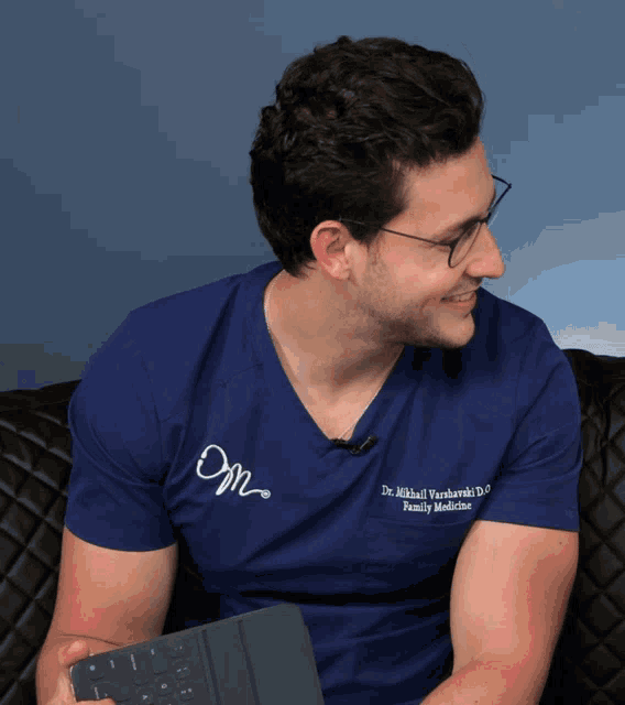 a man wearing a blue shirt that says dr. mikhail varshavski d.o family medicine