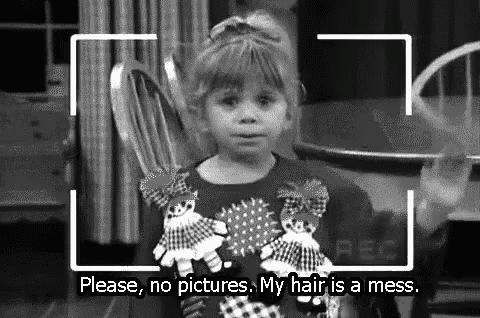 a little girl is sitting in a chair holding a stuffed animal and a camera is taking a picture of her .
