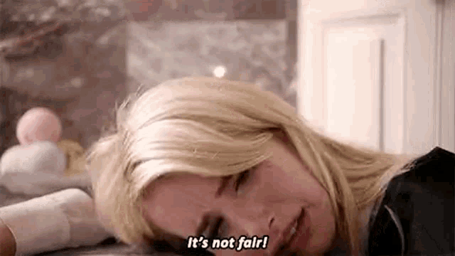 a woman is laying on the floor with her head on the floor and saying `` it 's not fair ! ''