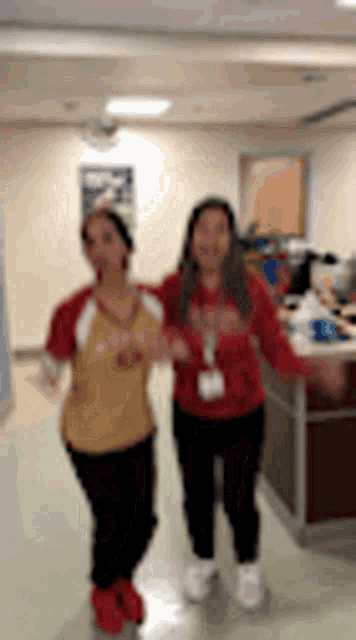 two women are dancing together in a hallway while holding hands .