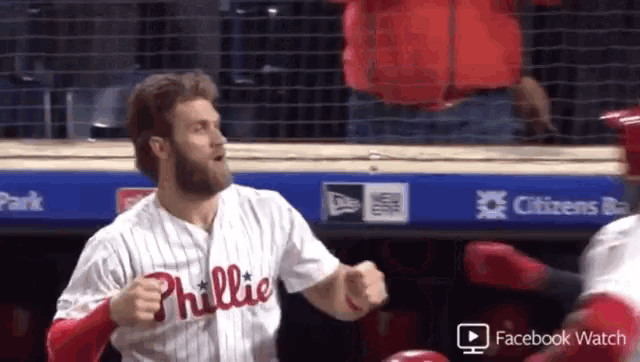 a baseball player wearing a phillies jersey is running in the dugout
