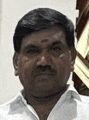 a man with a mustache is wearing a white shirt and standing in front of a wall .