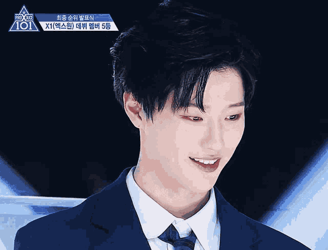 a man in a suit and tie is smiling in front of a sign that says ' 101 '