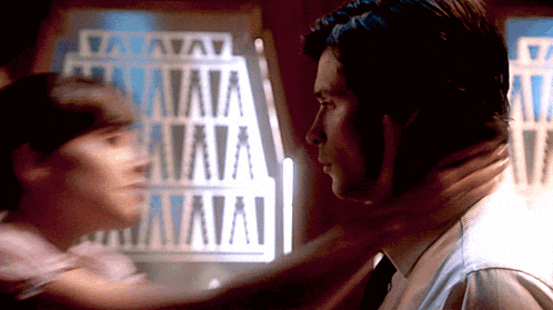 a man holds another man 's neck in front of a sign that says " vava "
