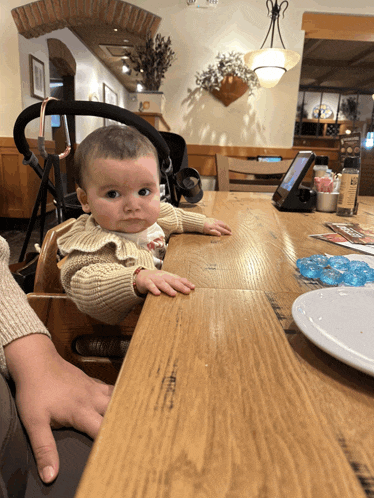 a baby is sitting at a wooden table with a menu on it