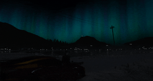 the aurora borealis is visible in the night sky over a city