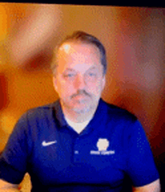 a man with a beard is wearing a blue shirt with a nike logo on it .
