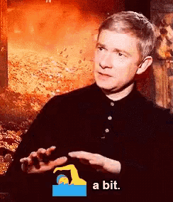 a man in a black shirt says a bit in front of a fire