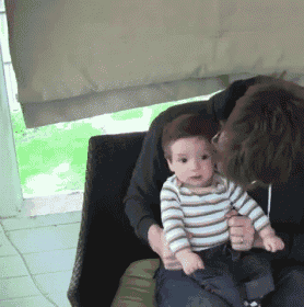 a man is holding a baby in his lap and kissing it