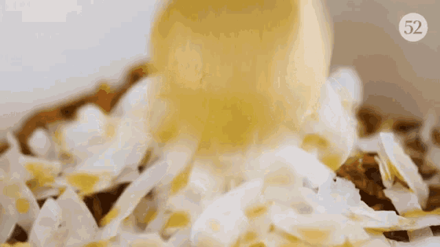 a piece of butter is being poured into a bowl of coconut flakes