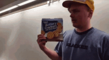 a man is holding a box of buttery crackers in his hand