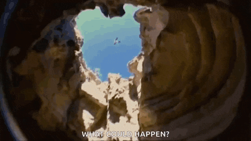 a bird is flying through a hole in a rock formation .