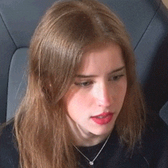 a young woman with long hair is sitting in a chair wearing a necklace .