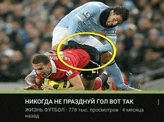 a soccer player is laying on the ground while another player tries to tackle him .