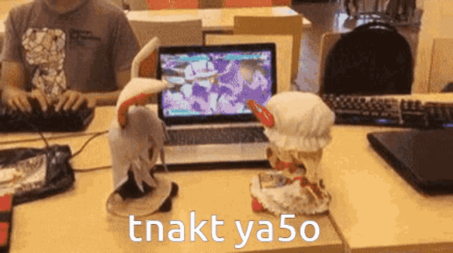 two stuffed animals are sitting on a table in front of a laptop with the words tnakt ya50 on the bottom