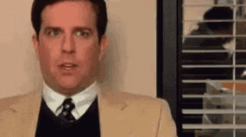 a man in a suit and tie is standing in front of a window with blinds .