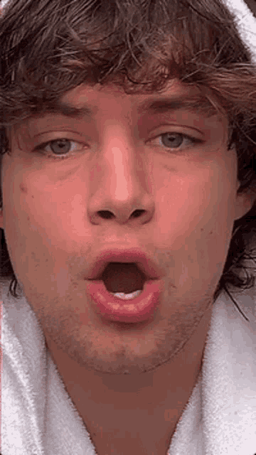 a close up of a man 's face with his mouth open and a towel around his head .
