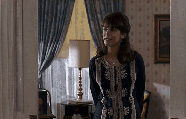 a woman in a blue dress stands in a room