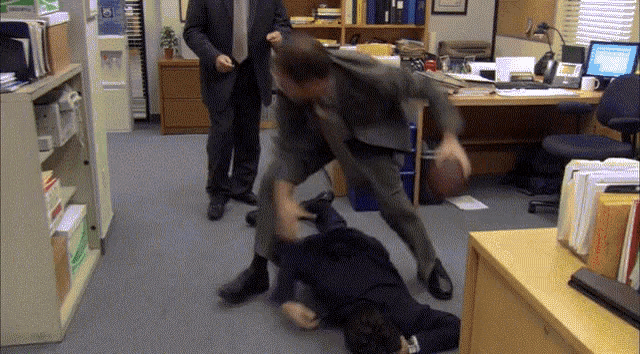a man in a suit and tie is fighting another man on the floor .