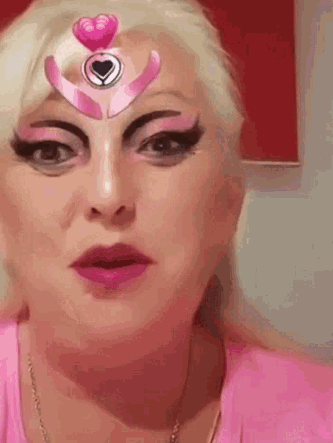 a woman with pink makeup on her face and a pink heart on her forehead .
