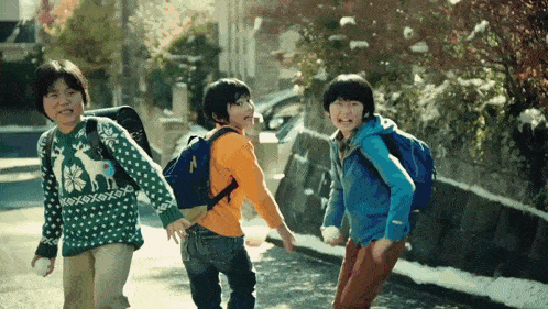 a boy wearing a sweater with a deer on it is walking with two other boys
