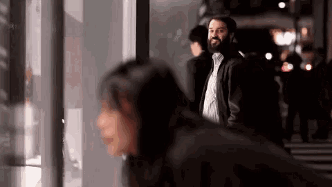 a man with a beard is standing next to a woman in a crowded street .
