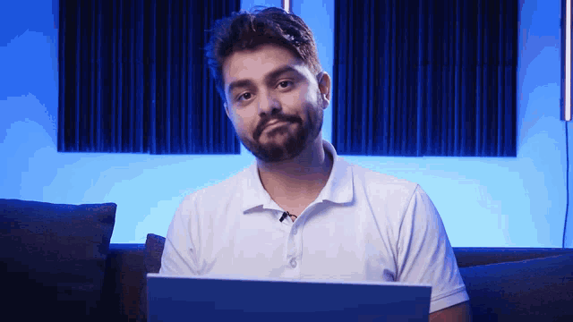 a man in a white shirt is sitting in front of a laptop
