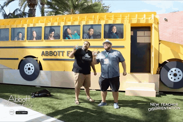 two men are standing in front of a large yellow school bus that says abbott elementary