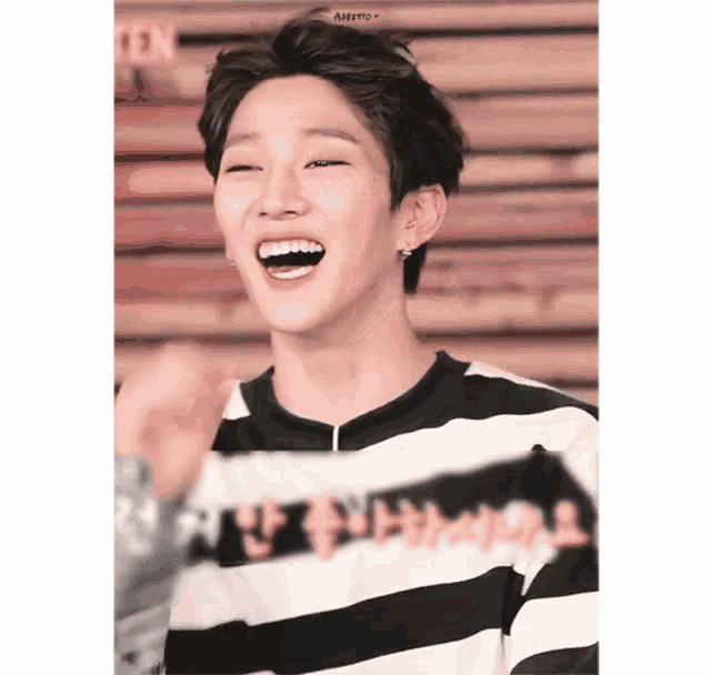 a young man wearing a black and white striped shirt with chinese writing on it is laughing